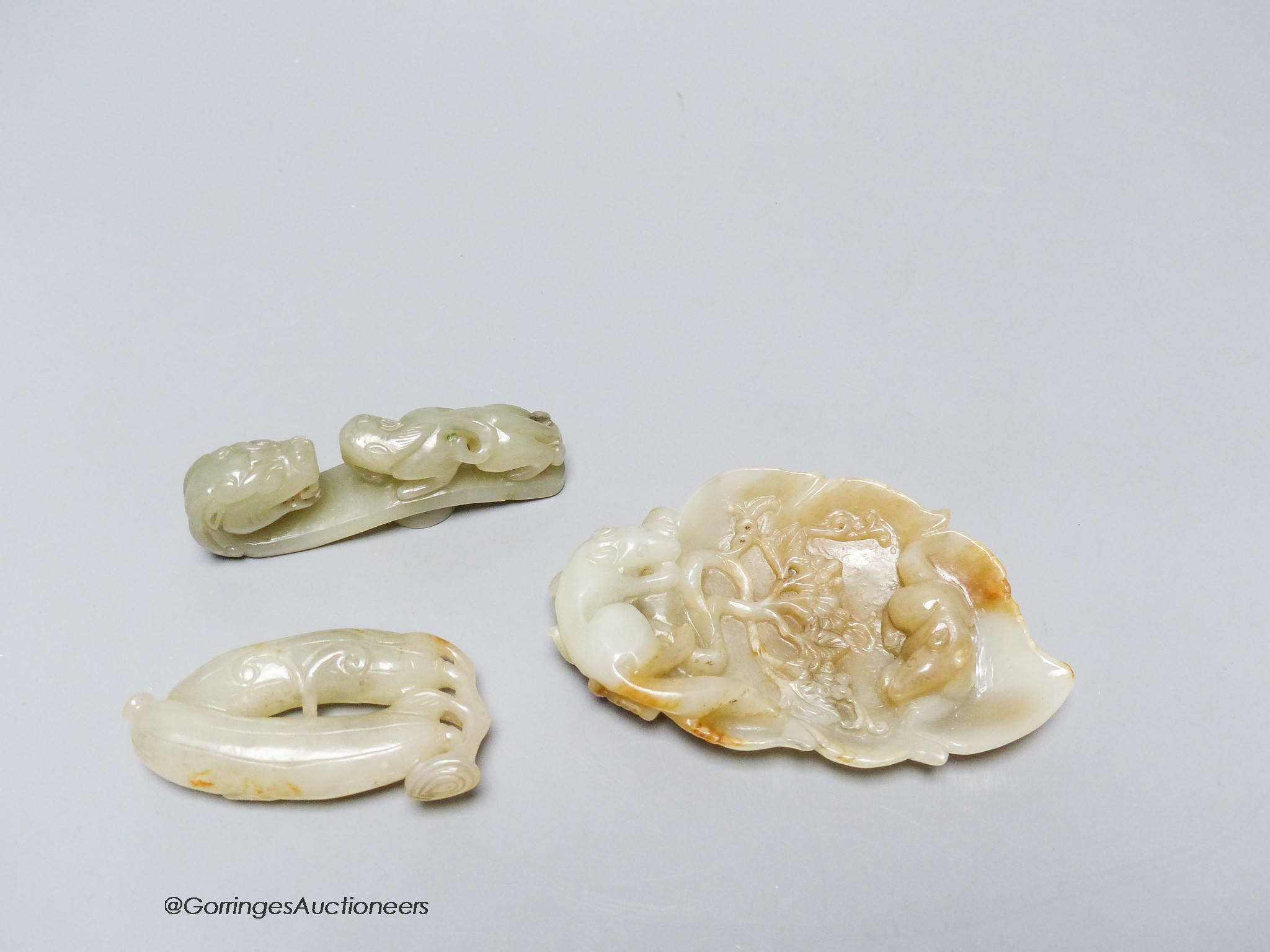 Three Chinese celadon jade carvings, a 'squirrel' brushwasher, 'dragon' belt hook and a carving of bitter melons, 7.5 - 11cm